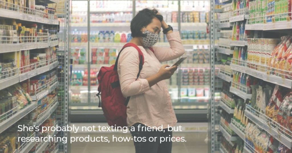 Image of woman shopping with a smart phone as an example of the hybrid shopping business trend.