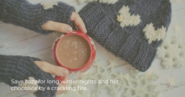 Image of person with mittens and hot chocolate to illustrate coziness.